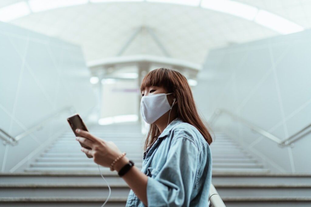 woman wearing a face mask and holding a smartphone 4429651